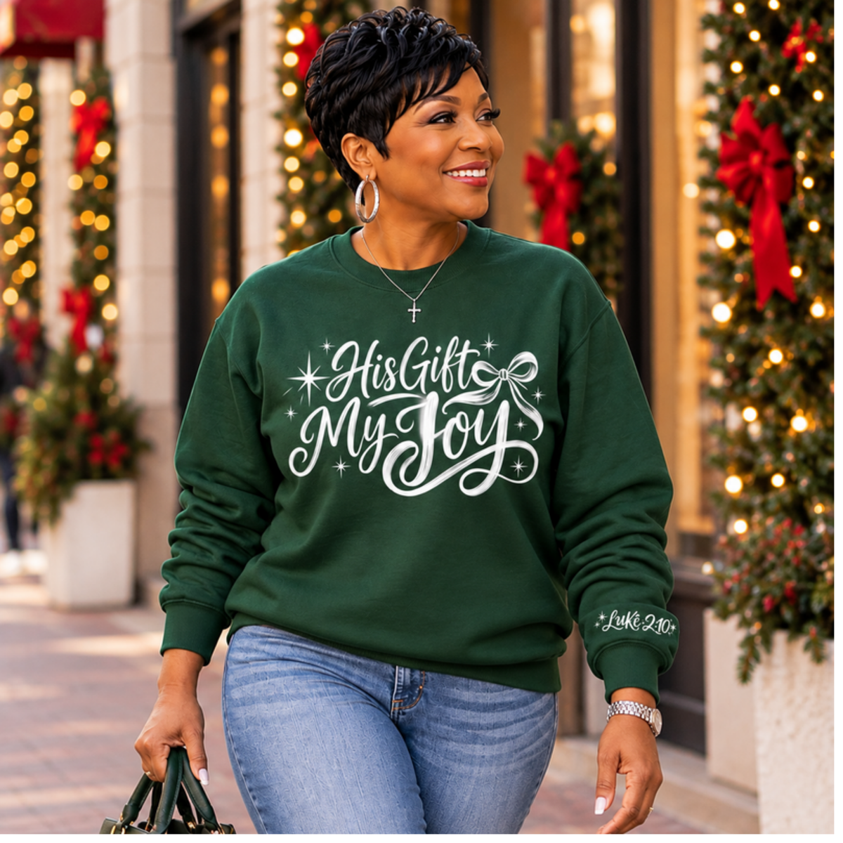 Woman wearing forest green His Gift My Joy crewneck sweatshirt on a festive Christmas street